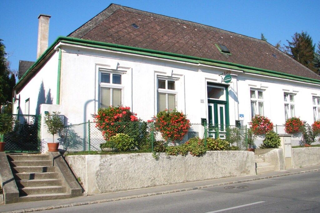 A white building with a green roof, a front door, and a staircase leading to the entrance.