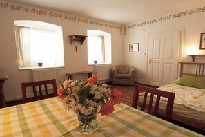 A room with a checkered tablecloth, a vase with flowers, a bed with a floral bedspread, and two windows with curtains. - 1 Hauerhof Winery 99 (Klosterneuburg)