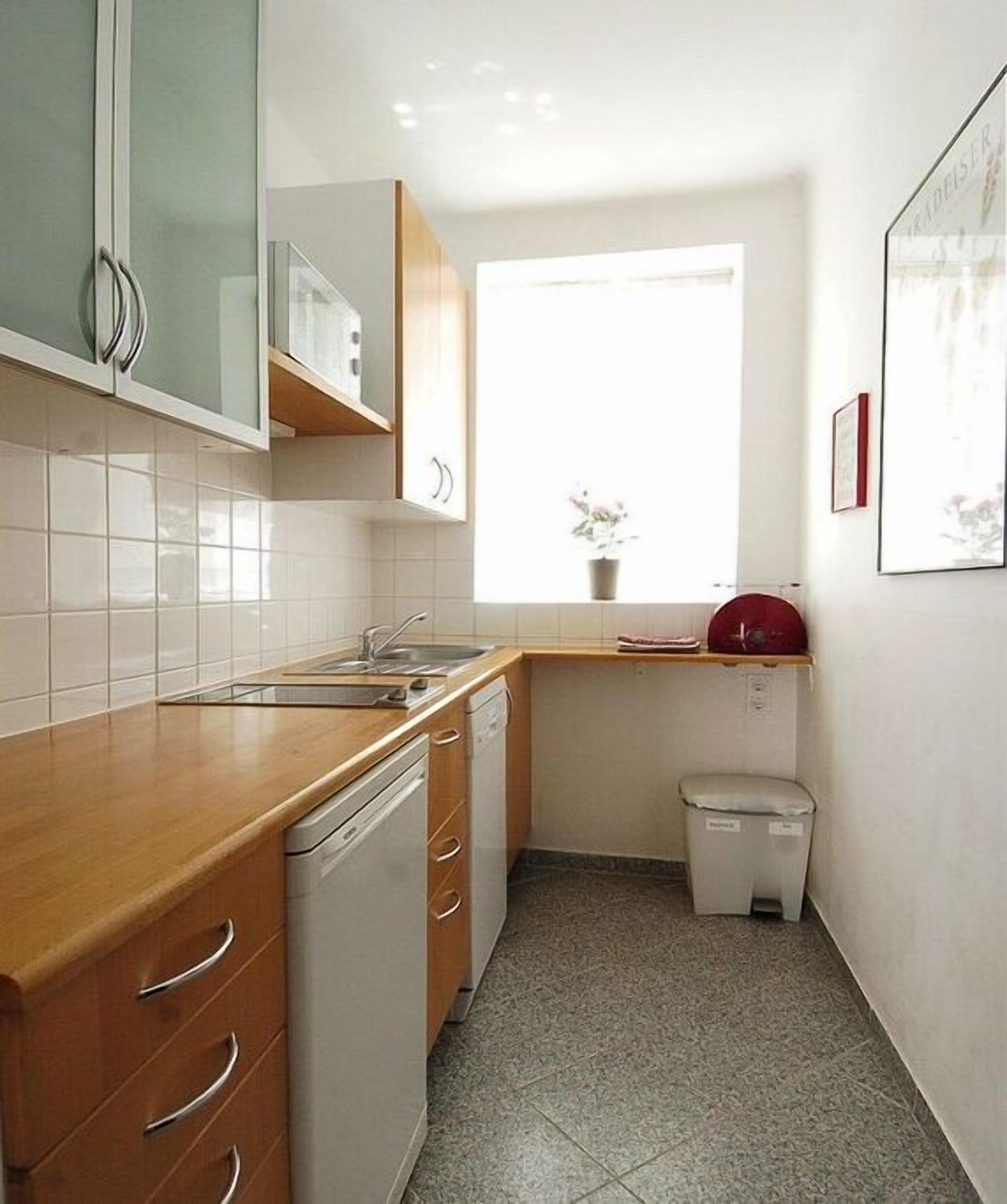 A compact kitchen with a dishwasher, a sink, and a small trash bin.