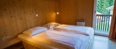 A wooden cabin bedroom with a bed, a bench, and a window.