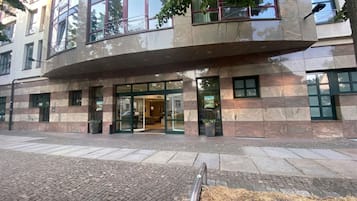 Ein modernes Gebäude mit einem geschwungenen Eingang, großen Fenstern und einem gepflasterten Gehweg.