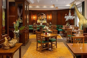 Een hotellobby met houten meubels, een groot schilderij en een girafbeeld.