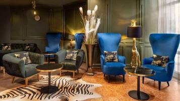 A lounge area with blue armchairs, a zebra-patterned rug, and a vase with dried plants.