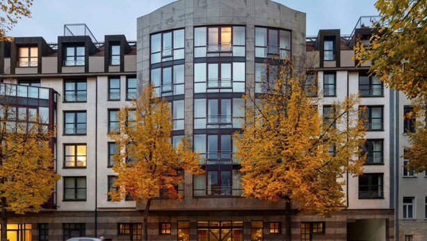 Et hotel med flere etager, en buet facade, store vinduer og en central indgang.
