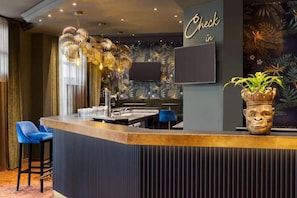 Een bar met een incheckbord, een flatscreen televisie en een decoratieve plant.