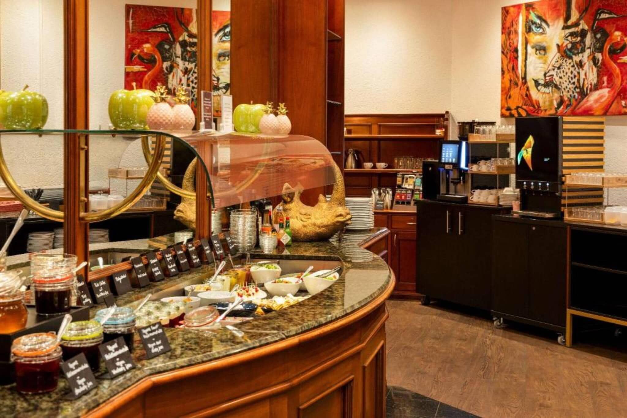 A hotel breakfast area with a buffet setup, including various food items and condiments.