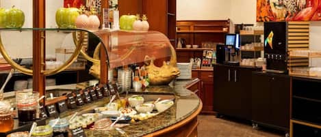 Un'area colazione in hotel con un buffet ricco di cibi e condimenti diversi.