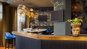 Eine Bar mit einer Rezeption, einem Flachbildfernseher und einer Zierpflanze.