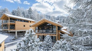 Uma cabana de madeira com varanda, rodeada por árvores cobertas de neve.