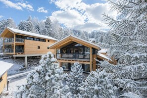 Eine Holzhütte mit Balkon, umgeben von schneebedeckten Bäumen.