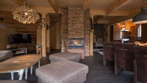 A cozy living room with a fireplace, wooden furniture, and a television. - Cabin in Turrach with sauna and Wi-Fi (Turrach)