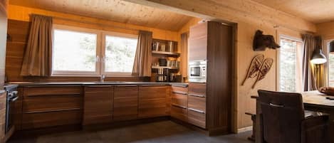 Ein Holzinterieur mit Küchenbereich, einem Esstisch mit Stühlen und einem großen Fenster.