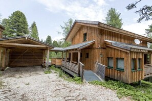 Puuinen mökki, jossa on katettu kuisti ja sorapäällysteinen ajotie.