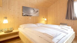 A wooden room with a bed, a wall-mounted picture, and two wall-mounted lamps. - Cabin in Turrach with sauna and Wi-Fi (Turrach)
