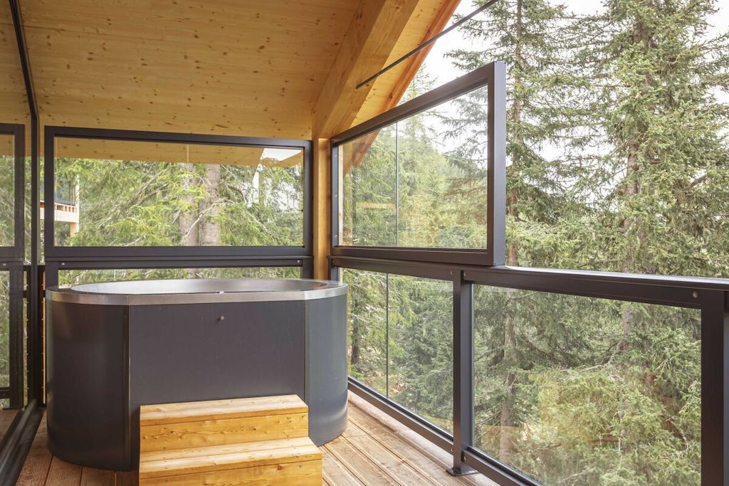 Een modern interieur met een houten terras, grote ramen en een jacuzzi.