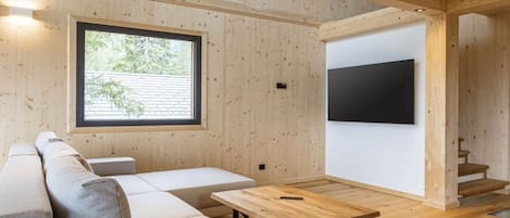 En modern inredning med ett träpanelat tak, ett stort fönster, en platt-TV, en soffa och ett träbord.