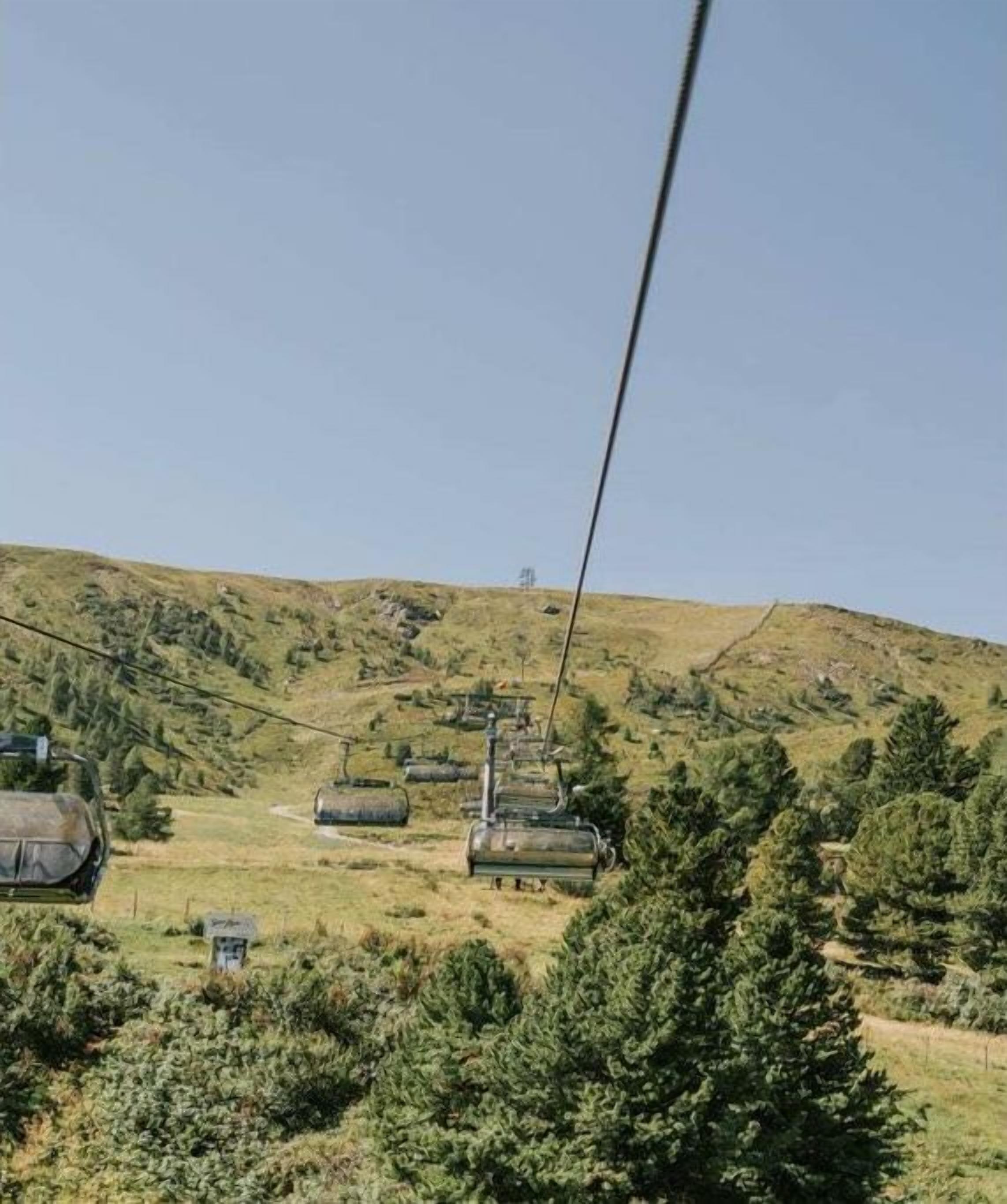 Un téléphérique traversant une région montagneuse, avec une végétation luxuriante et un ciel dégagé.