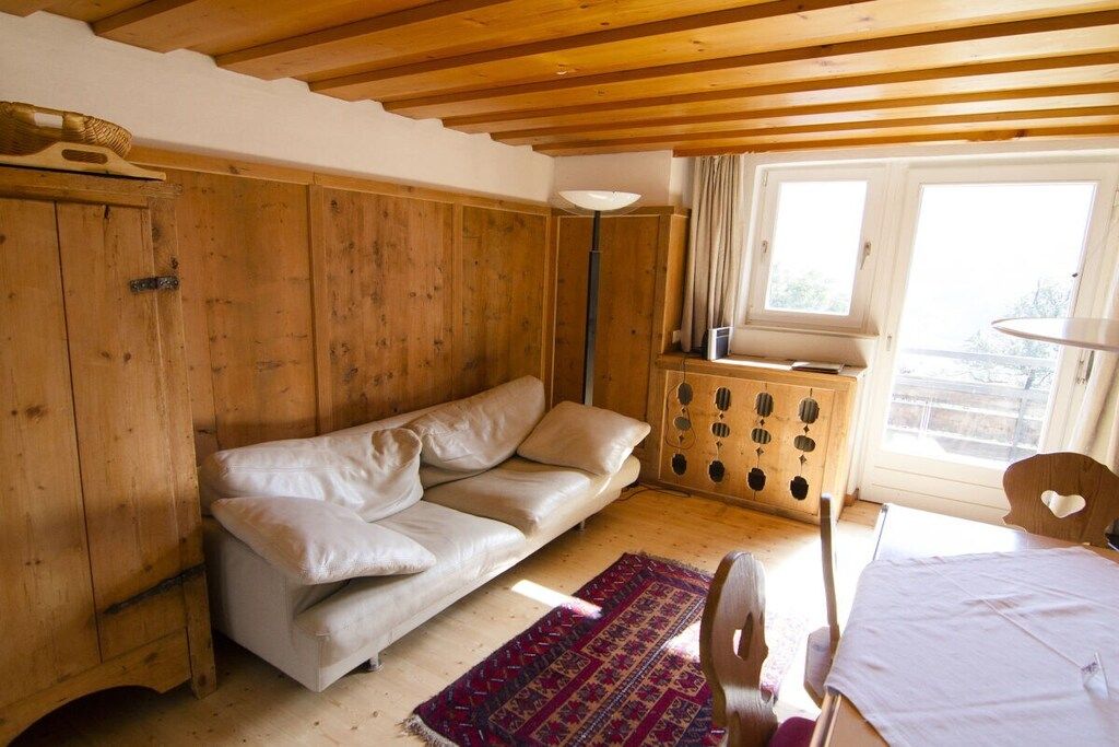 Una habitación con techo de madera, un sofá, una cama, un ventanal y un armario.
