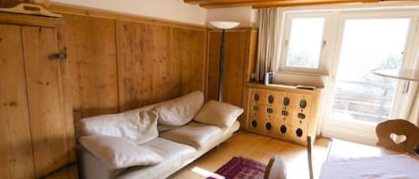 Una habitación con techo de madera, un sofá, una cama, un ventanal y un armario.