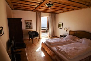A bedroom with a large bed, a desk, a chair, and a view of the outdoors through a door. - Holiday apartment with 1 bedroom (Telfes)