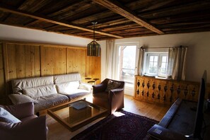 Una sala de estar acogedora, con techo de madera, un sofá, una mesa de centro y un tapete estampado.