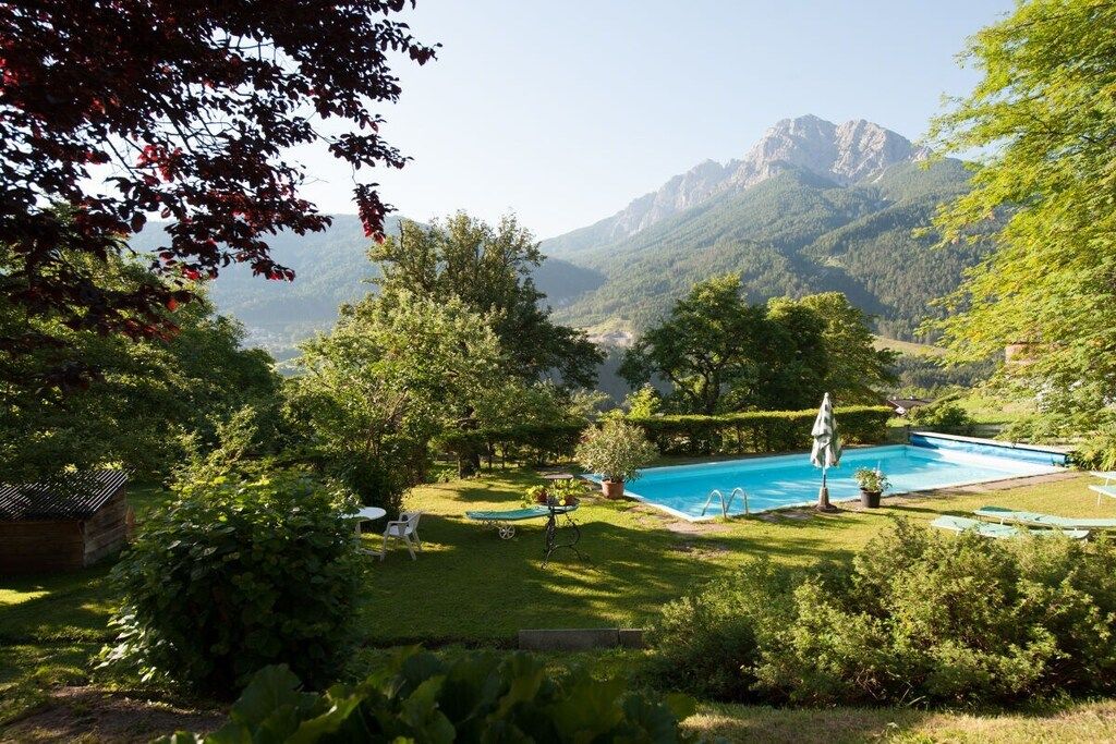 Una piscina rodeada de vegetación exuberante y montañas al fondo.