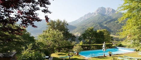 Una piscina rodeada de vegetación exuberante y montañas al fondo.