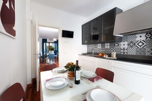 Una cocina moderna con comedor, televisor sobre la encimera y azulejos decorativos en la salpicadero.