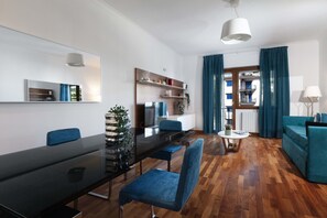 A modern living room with a dining area, a TV, and a view of the outside. - Aranci33 (Sorrento)