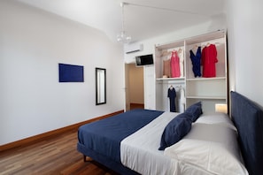 Ein Schlafzimmer mit einem Bett, einem Kleiderschrank, einem Fernseher und einer Wand-Klimaanlage.