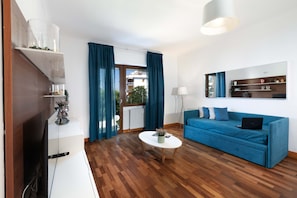 Ein modernes Wohnzimmer mit einem blauen Sofa, einem weißen Couchtisch und einem Fernseher auf einem Holzschrank.