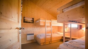 A wooden interior with bunk beds, a radiator, and a painting on the wall. - Cabin in Turrach with sauna and balcony (Turrach)