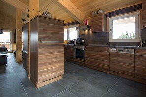 Eine moderne Küche mit Holzschränken, einem eingebauten Ofen und einem großen Fenster.