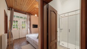 Un dormitorio con una cama, una escalera de madera, un televisor y una ventana con cortinas.