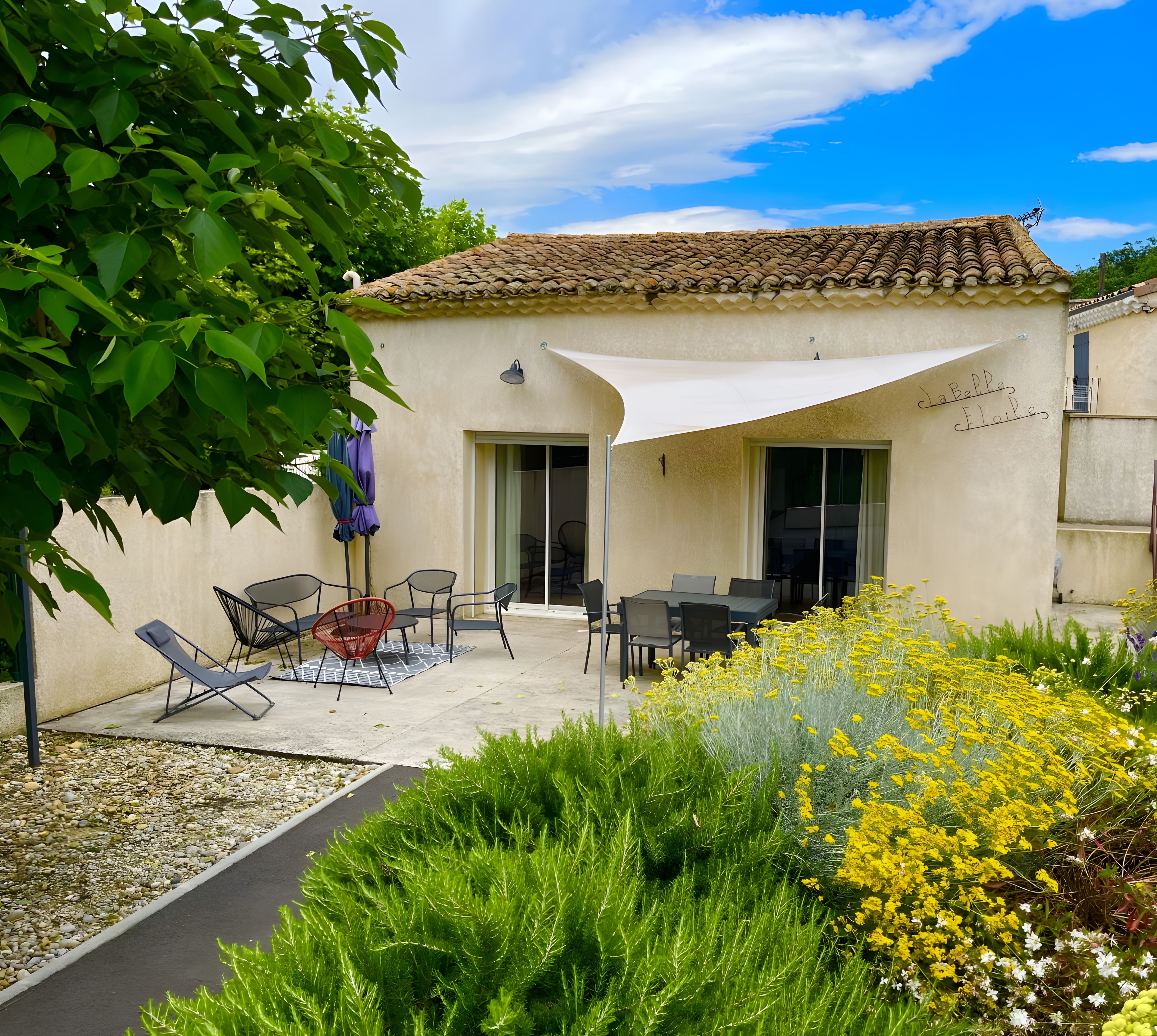 A patio with outdoor furniture, a covered seating area, and a garden with yellow flowers.