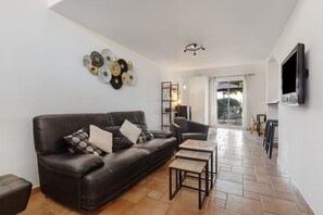 A modern living room with a leather sofa, a coffee table, and a wall-mounted TV.