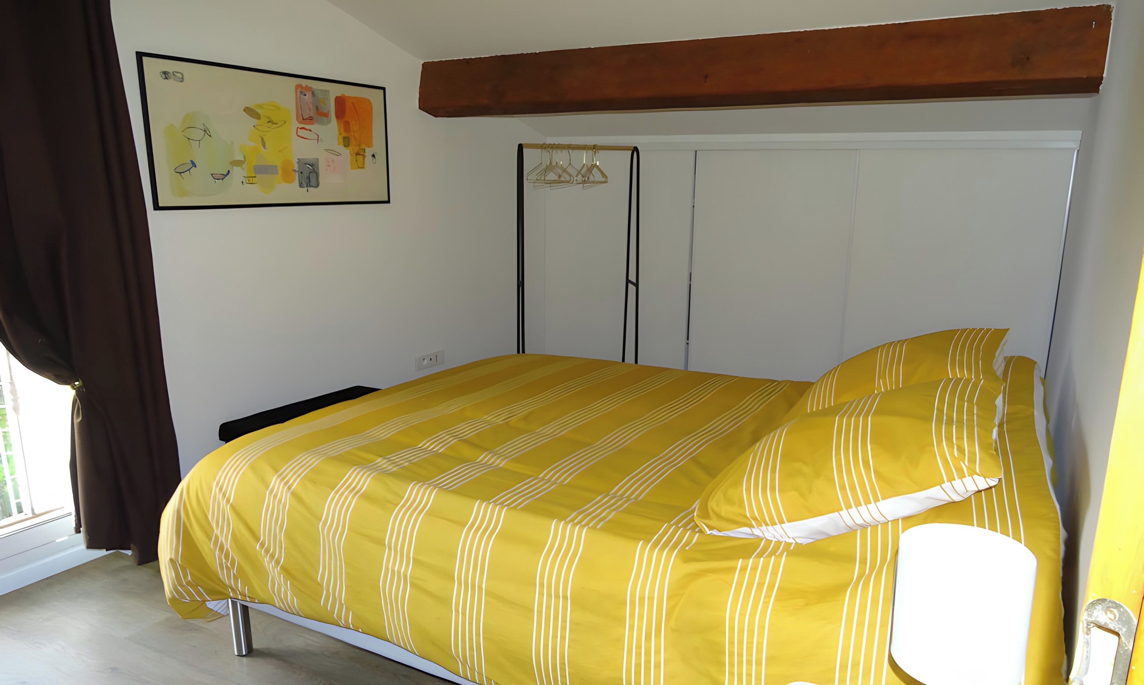 Ein Schlafzimmer mit einem Bett, einem Kleiderschrank und einem Bild an der Wand.