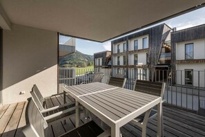 Un balcó amb taula i cadires, amb vistes a un paisatge de muntanya.