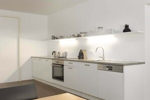 A modern kitchen with white cabinetry, a built-in oven, a dishwasher, and a countertop with various kitchen items. - Apartment in Rohrmoos-Untertal with sauna (Rohrmoos-Untertal)
