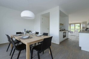 A modern dining area with a wooden table set for four, black chairs, and a white pendant light. - Apartment in Rohrmoos-Untertal with sauna (Rohrmoos-Untertal)