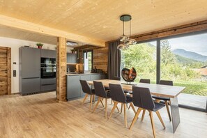 Eine moderne Küche mit Essbereich, Holzboden und großen Fenstern.