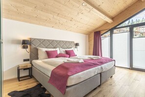 A bedroom with a large bed, wooden ceiling, and a view through a sliding door. - Apartment in Haus im Ennstal with sauna (Haus im Ennstal)