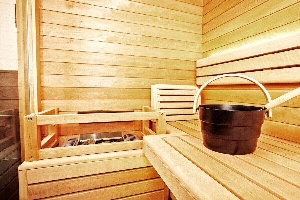 Uma sauna com bancos de madeira e um balde preto.