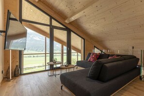 A modern interior with a large window, a sofa, and a small table. - Apartment in Haus im Ennstal with sauna (Haus im Ennstal)