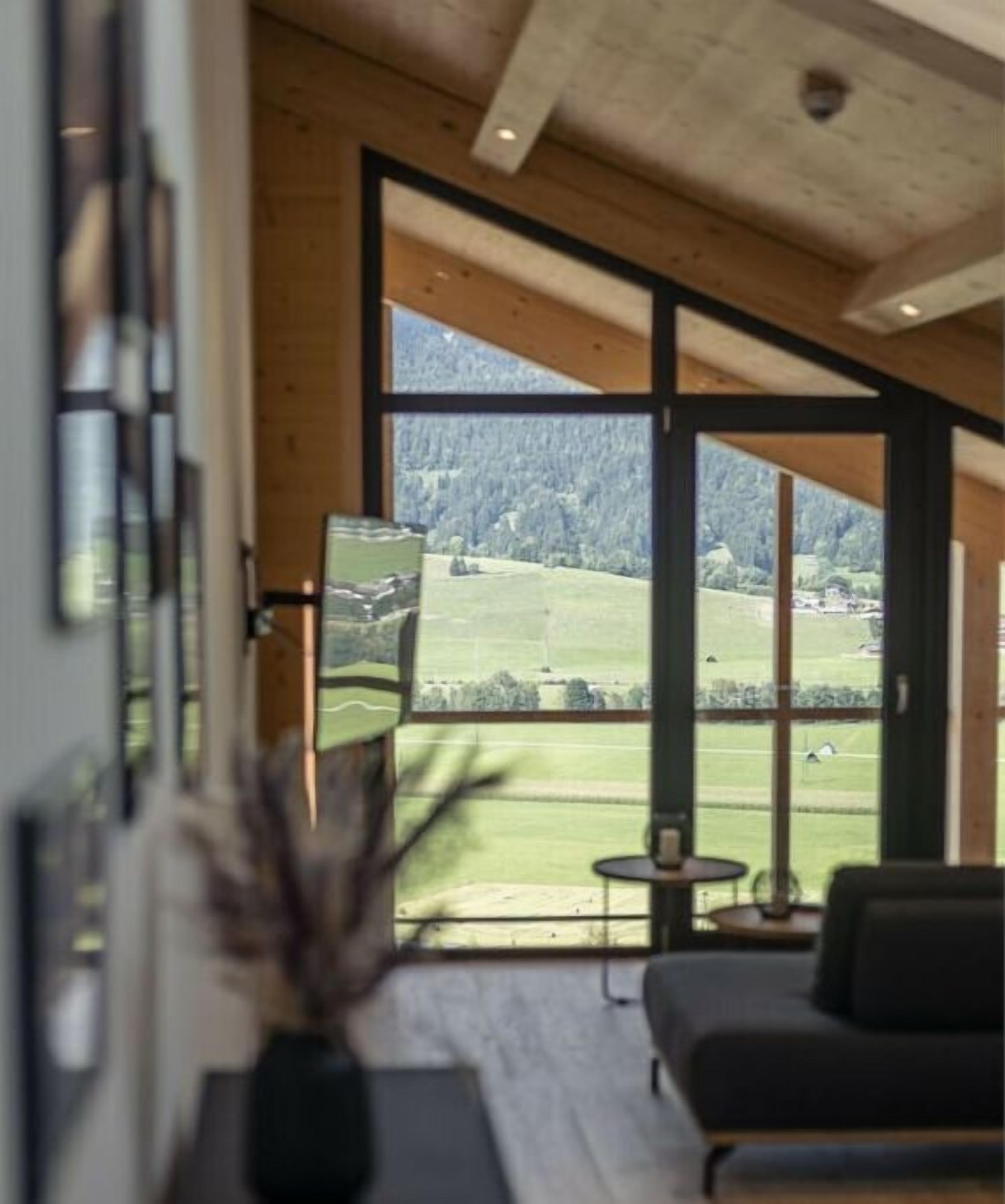 A room with a large window offering a view of a green landscape.