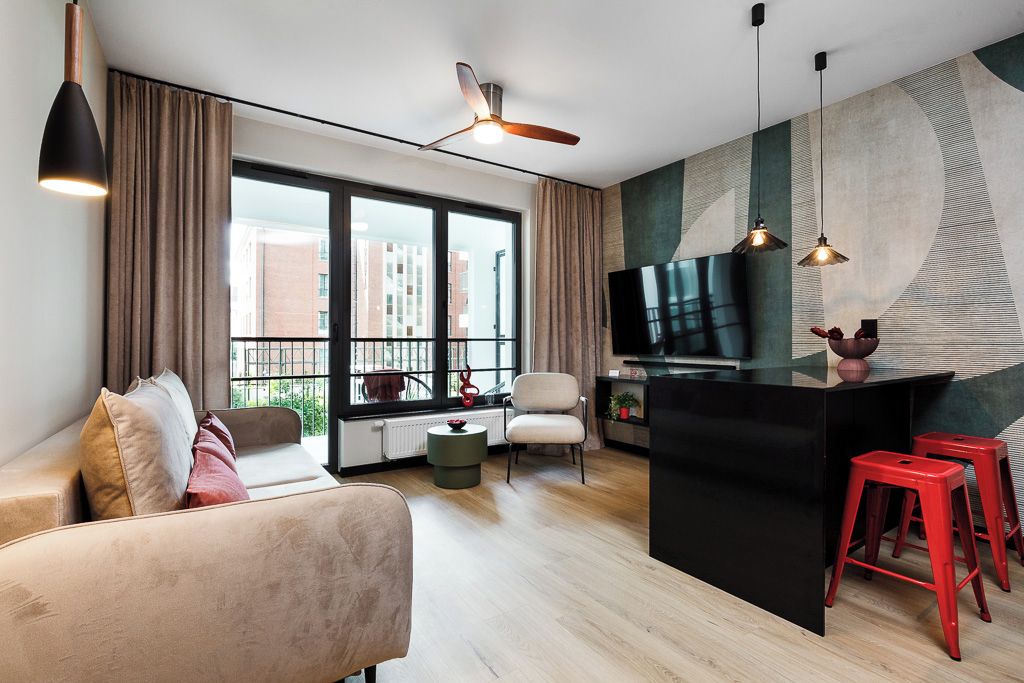 A modern living room with a sofa, a television, a dining area with stools, and a large window with a view of buildings.