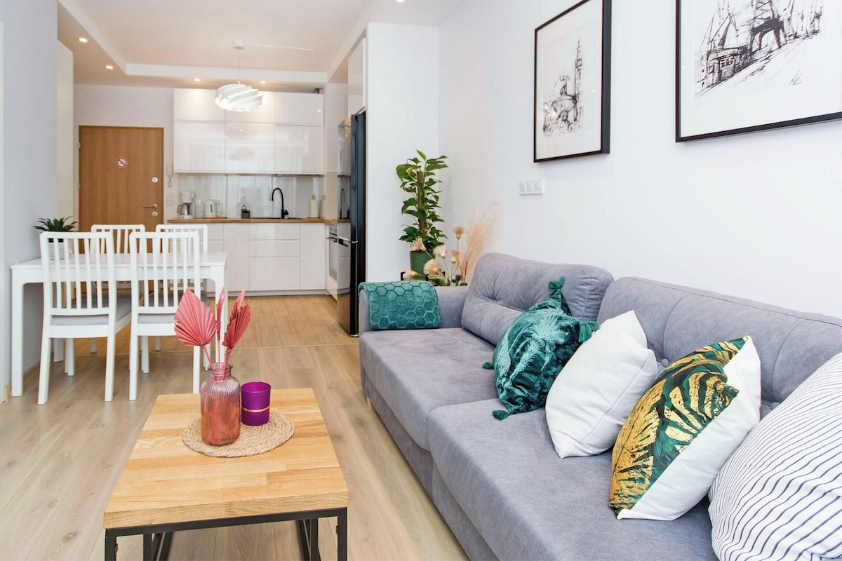 Ein modernes Wohnzimmer mit einem grauen Sofa, weißen Sesseln und einem Holztisch mit Dekoration.