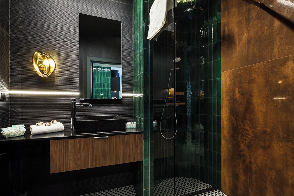A modern bathroom with a black sink, a mirror, and a glass-enclosed shower area.