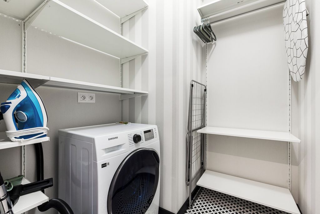 Een wasserette met een Samsung wasmachine, een strijkijzer en een droogrek.
