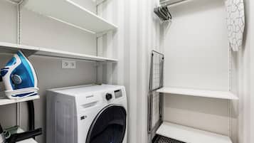 Een wasserette met een Samsung wasmachine, een strijkijzer en een droogrek.